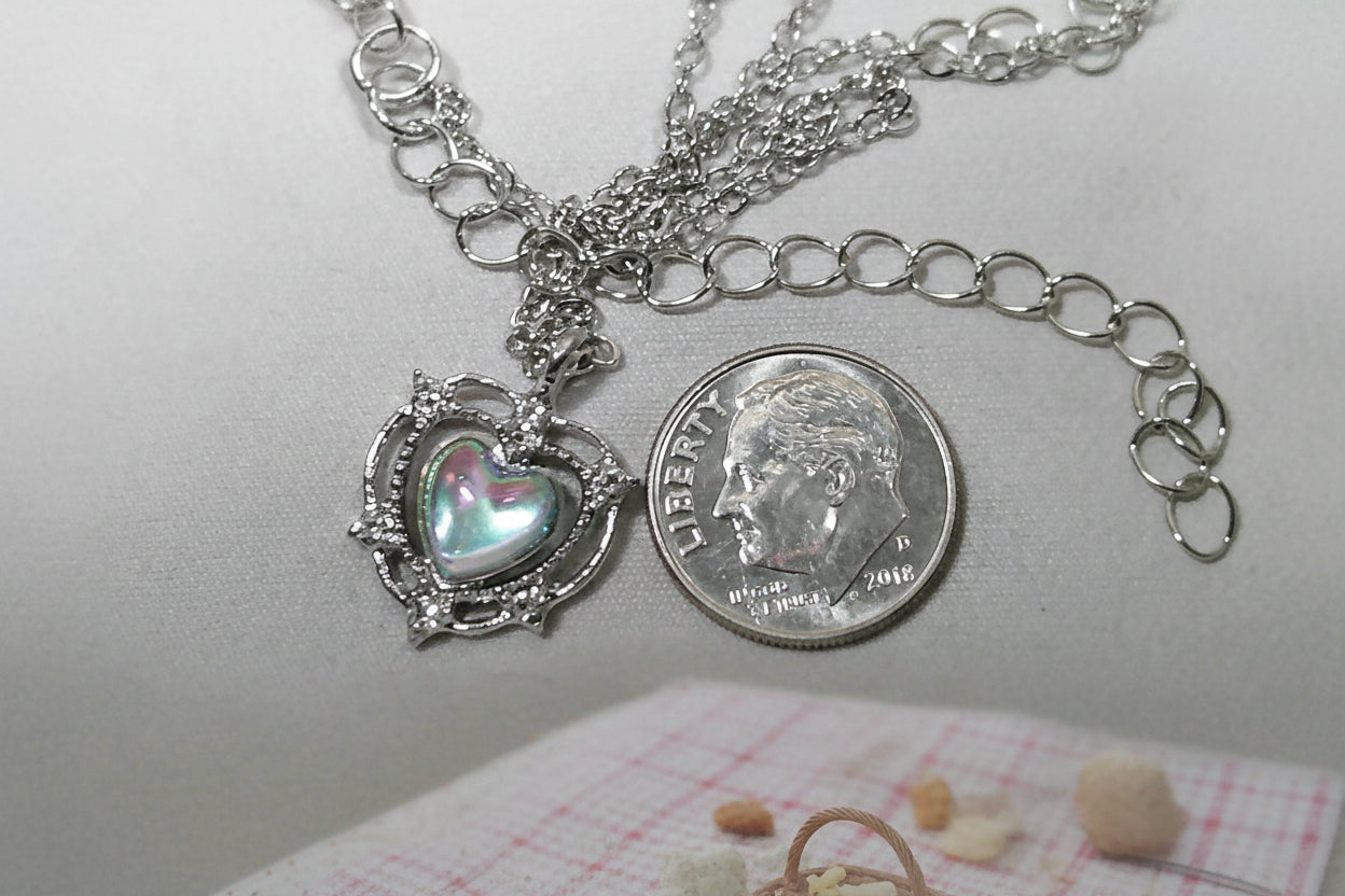 Necklace with a heart-shaped pendant next to a quarter on a gray background