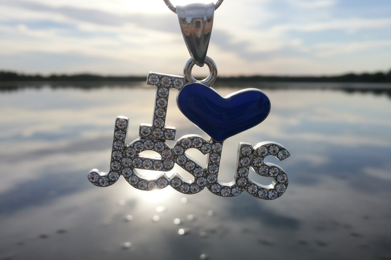Silver 'I Love Jesus' pendant with heart on a wooden surface