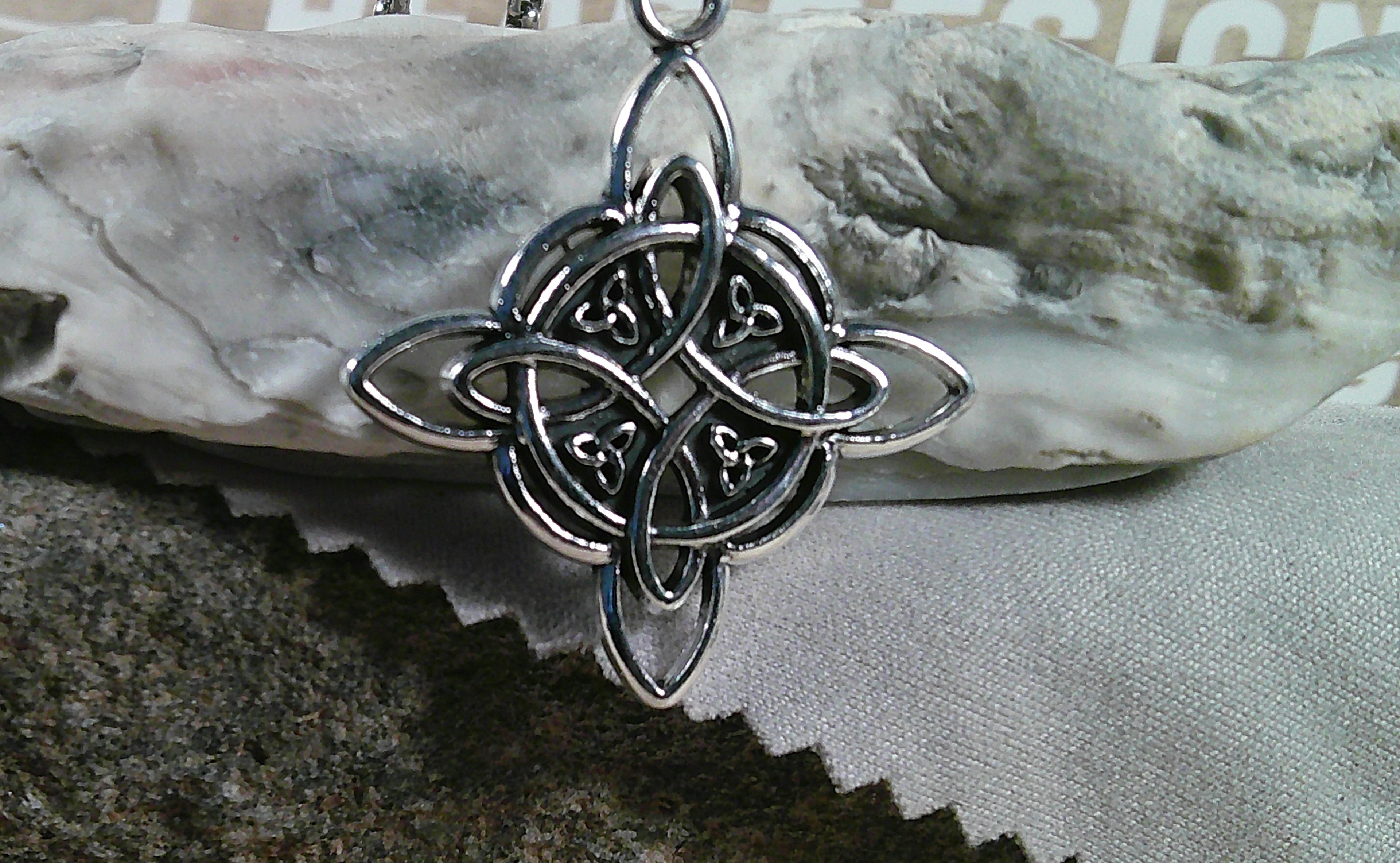 Silver Celtic knot pendant on a textured surface