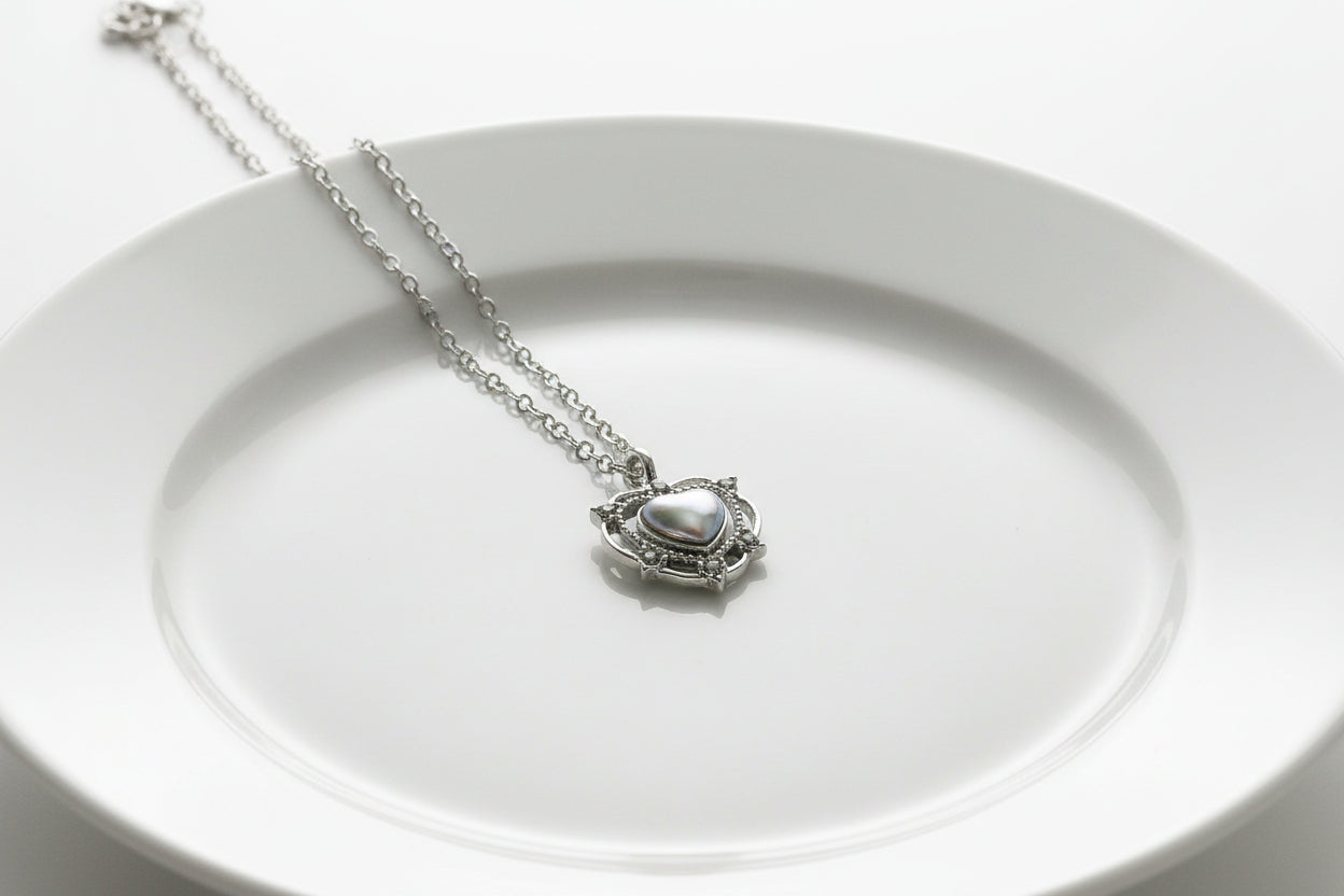 Silver pendant with a heart-shaped gemstone on a wooden surface