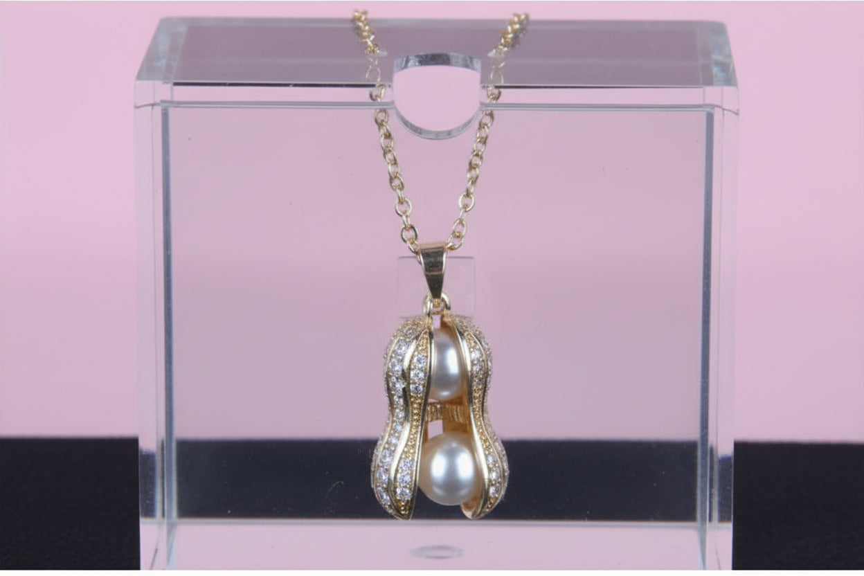 Gold pendant with pearls and crystals held between fingers