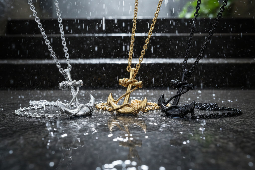 Three anchor-shaped necklaces in silver, gold, and black on a yellow background
